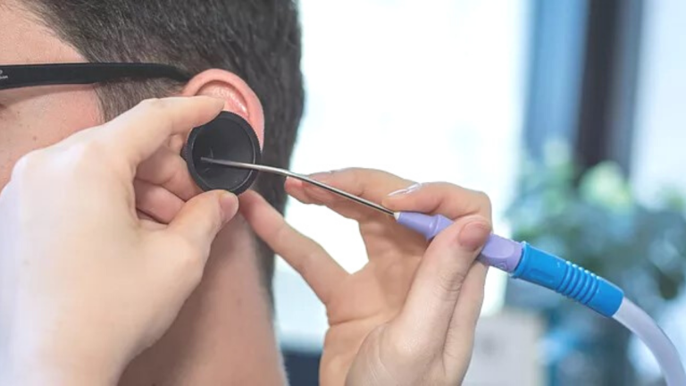 Close up of a young man having wax removed from his left ear using microsuction.